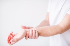 barbat care isi maseaza mana, durere periferica, fundal alb