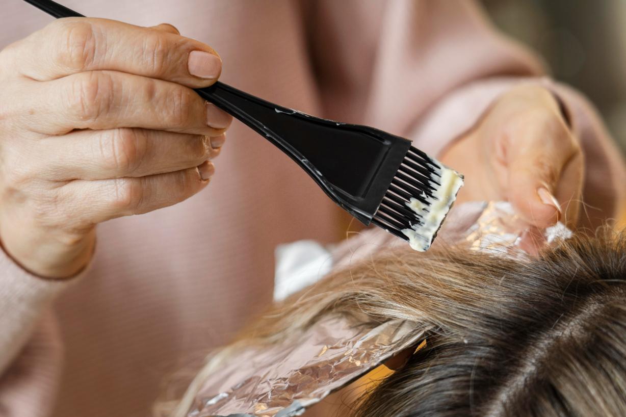 femeie la salon care isi vopseste parul